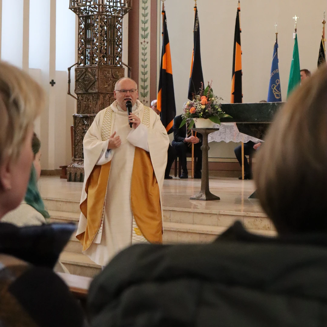 Das Bild zeigt Pfarrer Wölke bei seinem Abschiedgottesdienst. Er hält ein tragbares Mikrofon in seiner Hand und spricht zur Gemeinde.